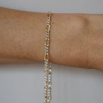Gold chain bracelet on a person's wrist against a neutral background