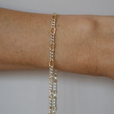 Gold chain bracelet on a person's wrist against a neutral background