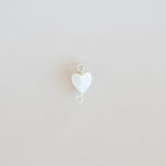 White heart-shaped pendant on a light beige background