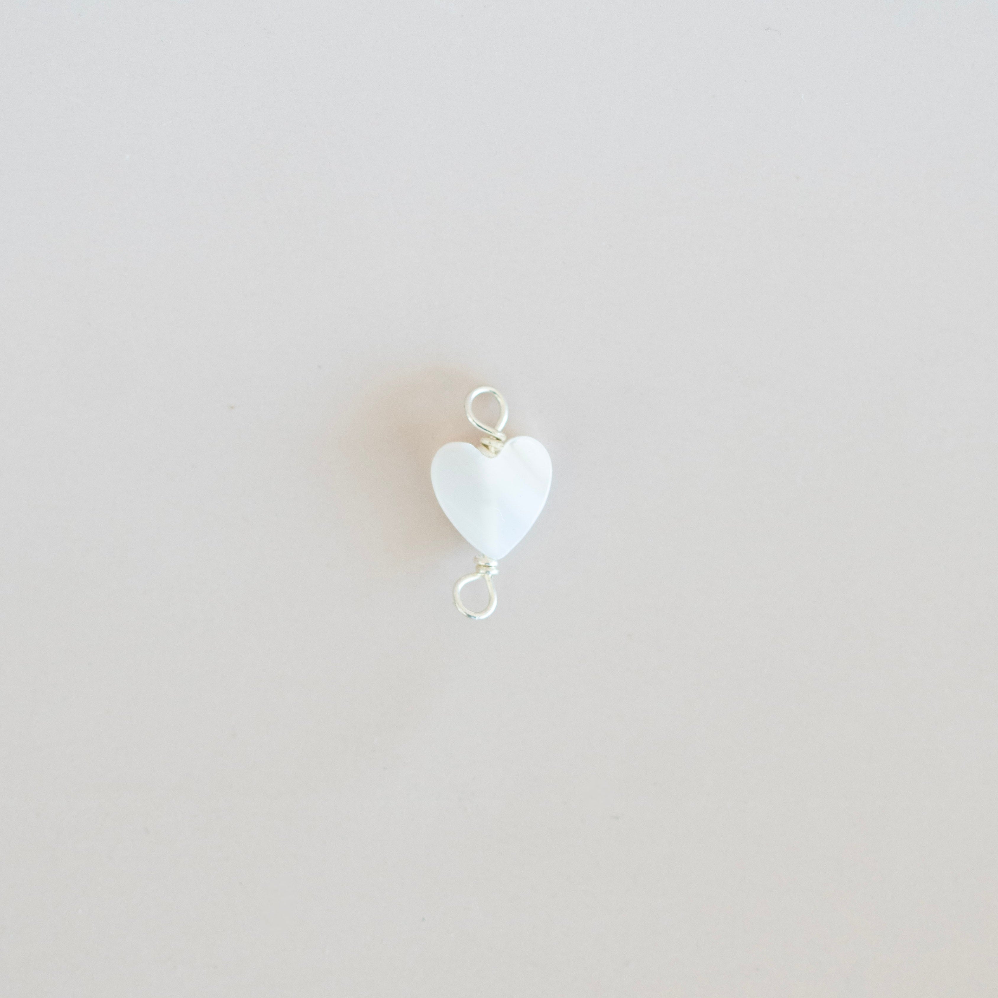 White heart-shaped pendant on a light beige background