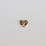 Gold heart-shaped number '2' charm on a light gray background