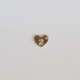 Gold heart-shaped number '2' charm on a light gray background