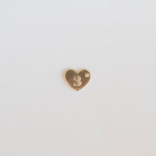 Heart-shaped gold charm with the number 3 on a light gray background