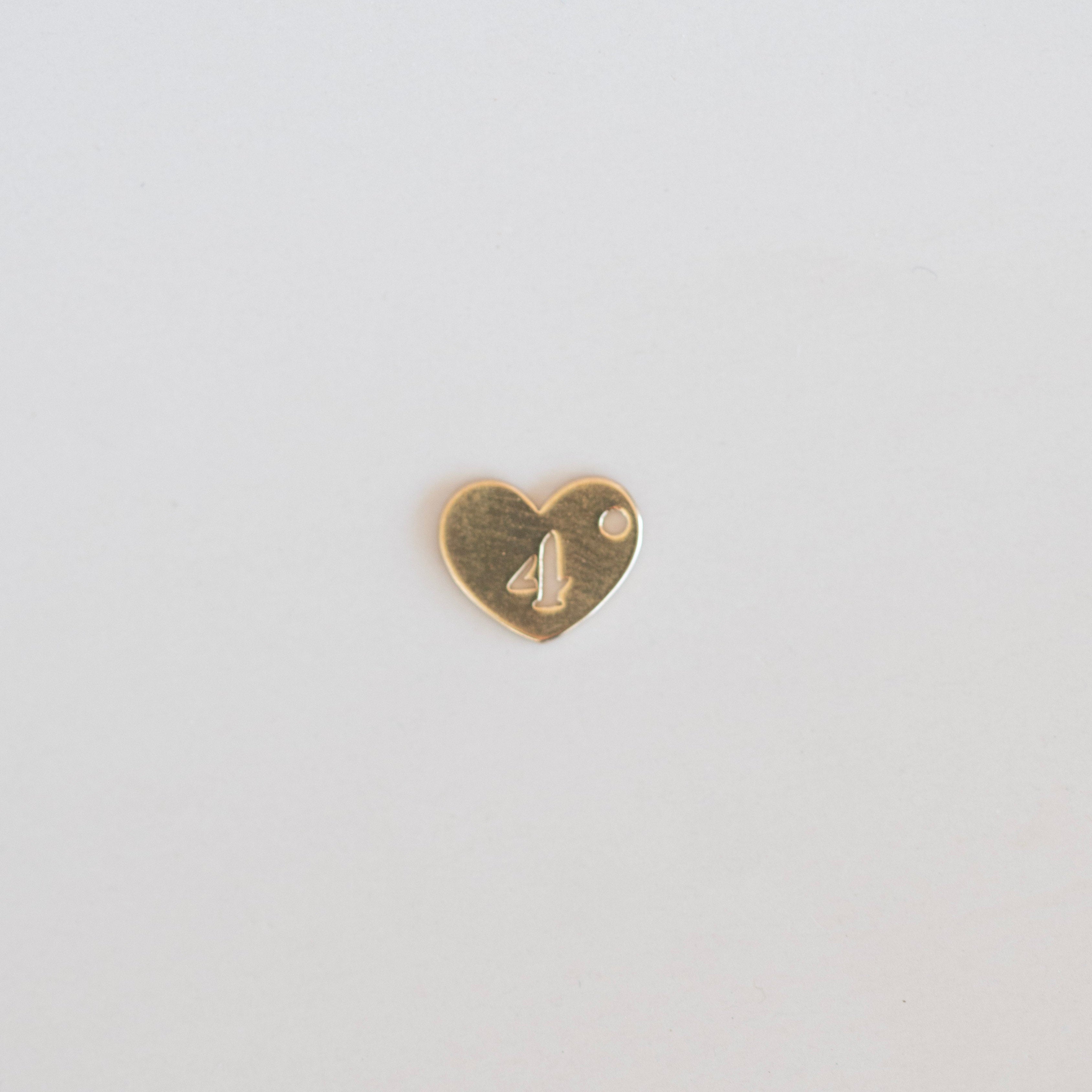 Heart-shaped gold charm with a number '4' on a light gray background