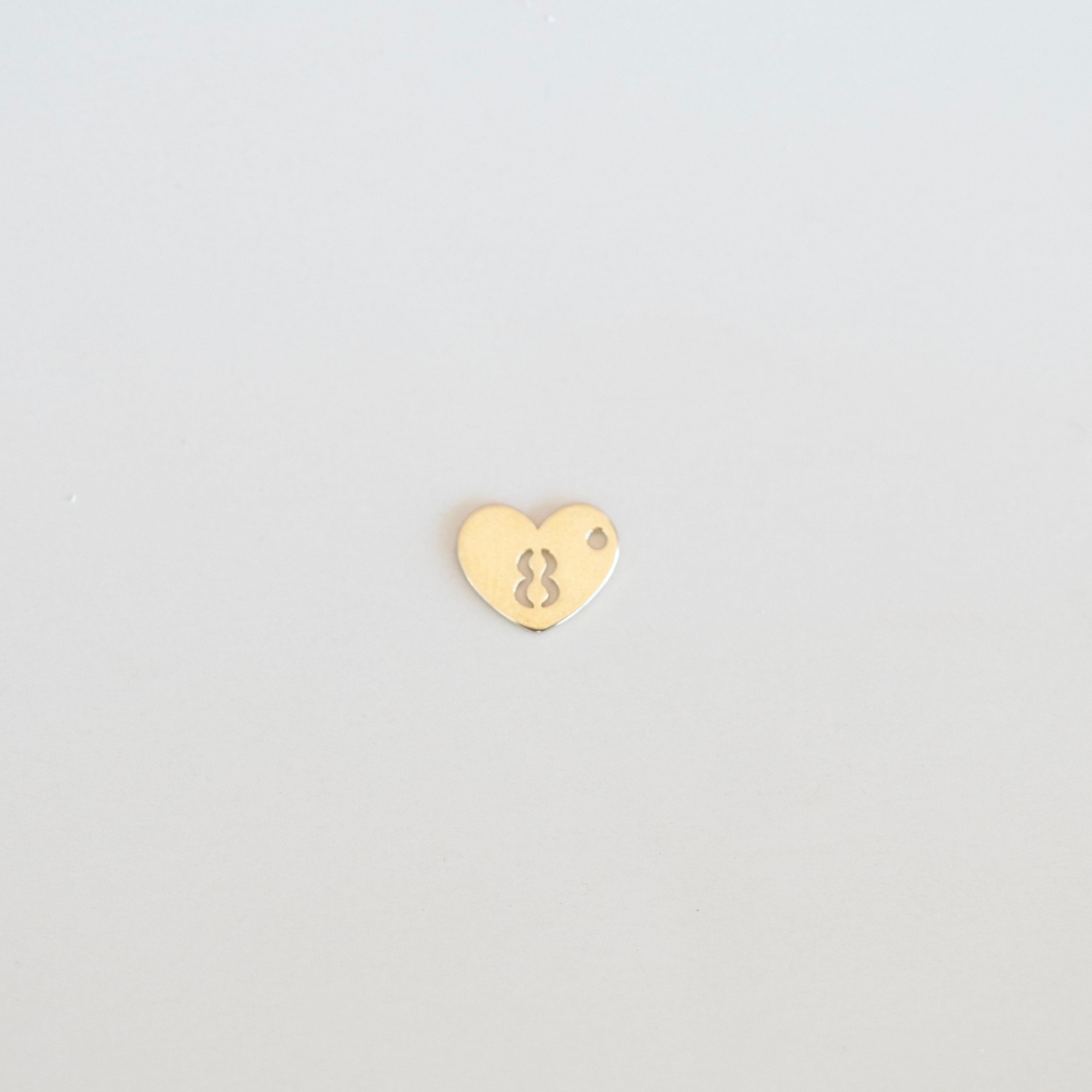 Gold heart-shaped charm with number '8' on a light gray background