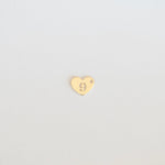 Gold heart-shaped earring on a light gray background