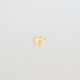 Gold heart-shaped earring on a light gray background
