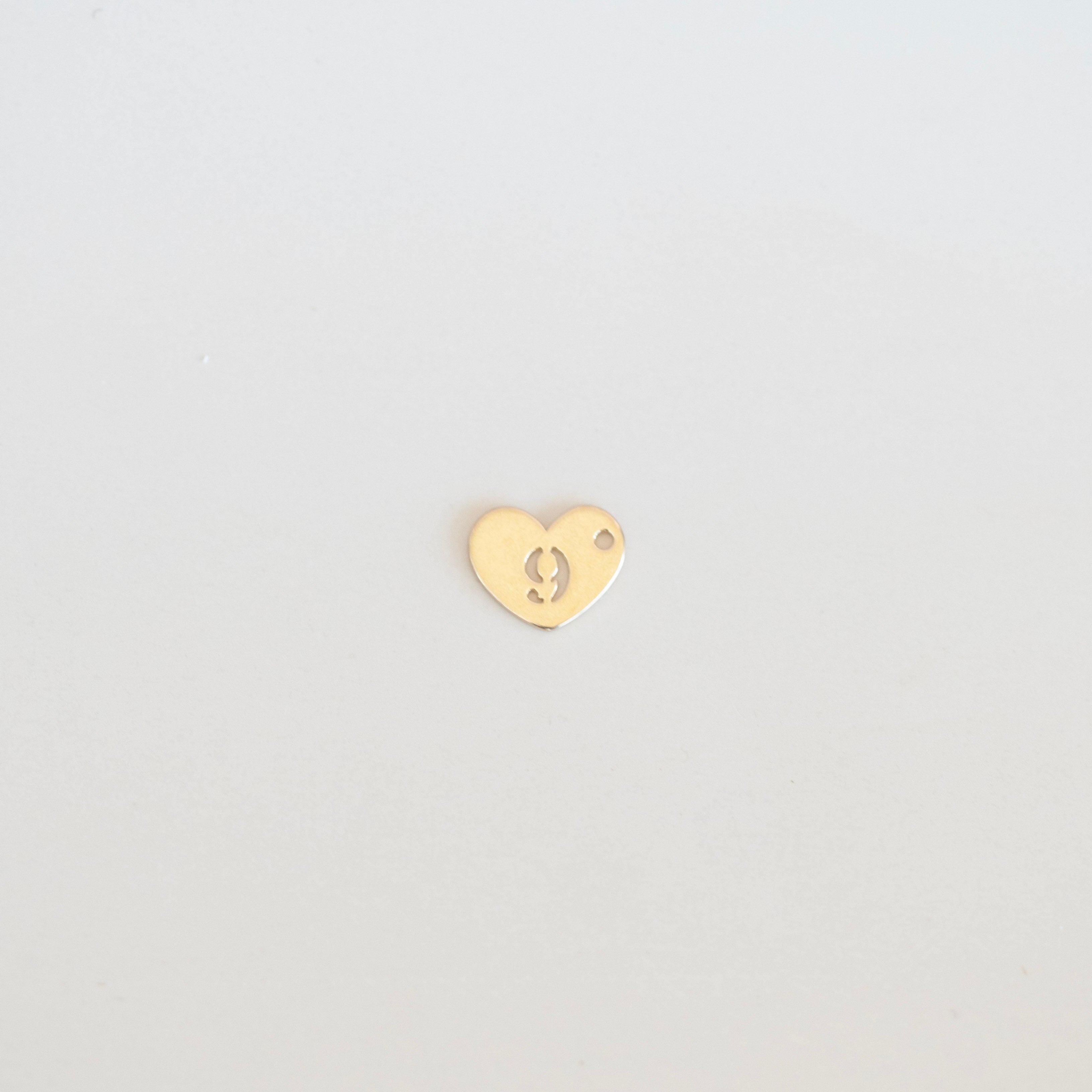 Gold heart-shaped earring on a light gray background