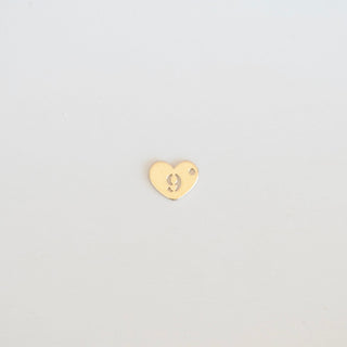 Gold heart-shaped earring on a light gray background