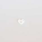 Small white heart-shaped object on a light gray background