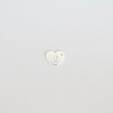 Small white heart-shaped object on a light gray background