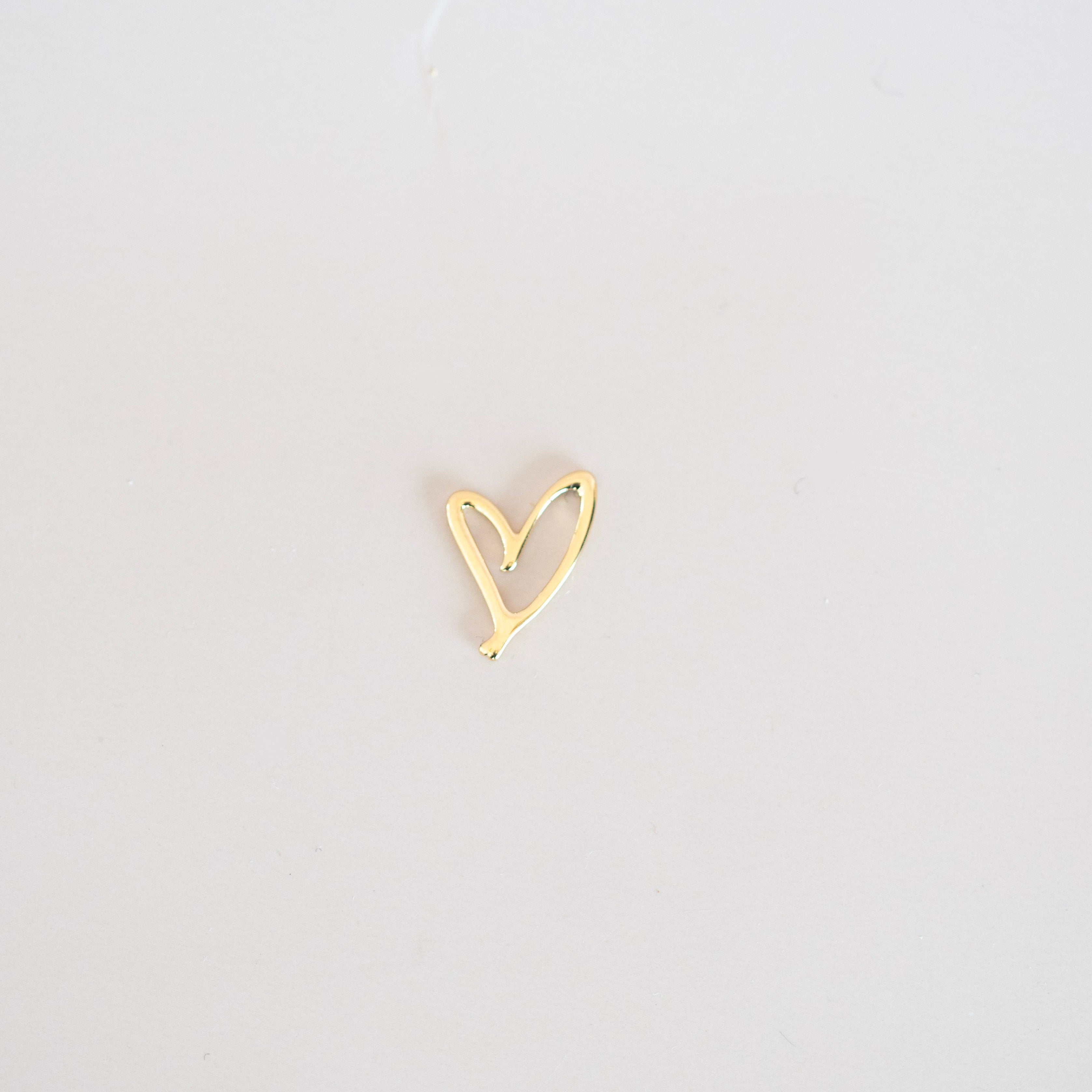 Gold heart-shaped earring on a light gray background