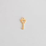 Gold key-shaped pendant on a light gray background