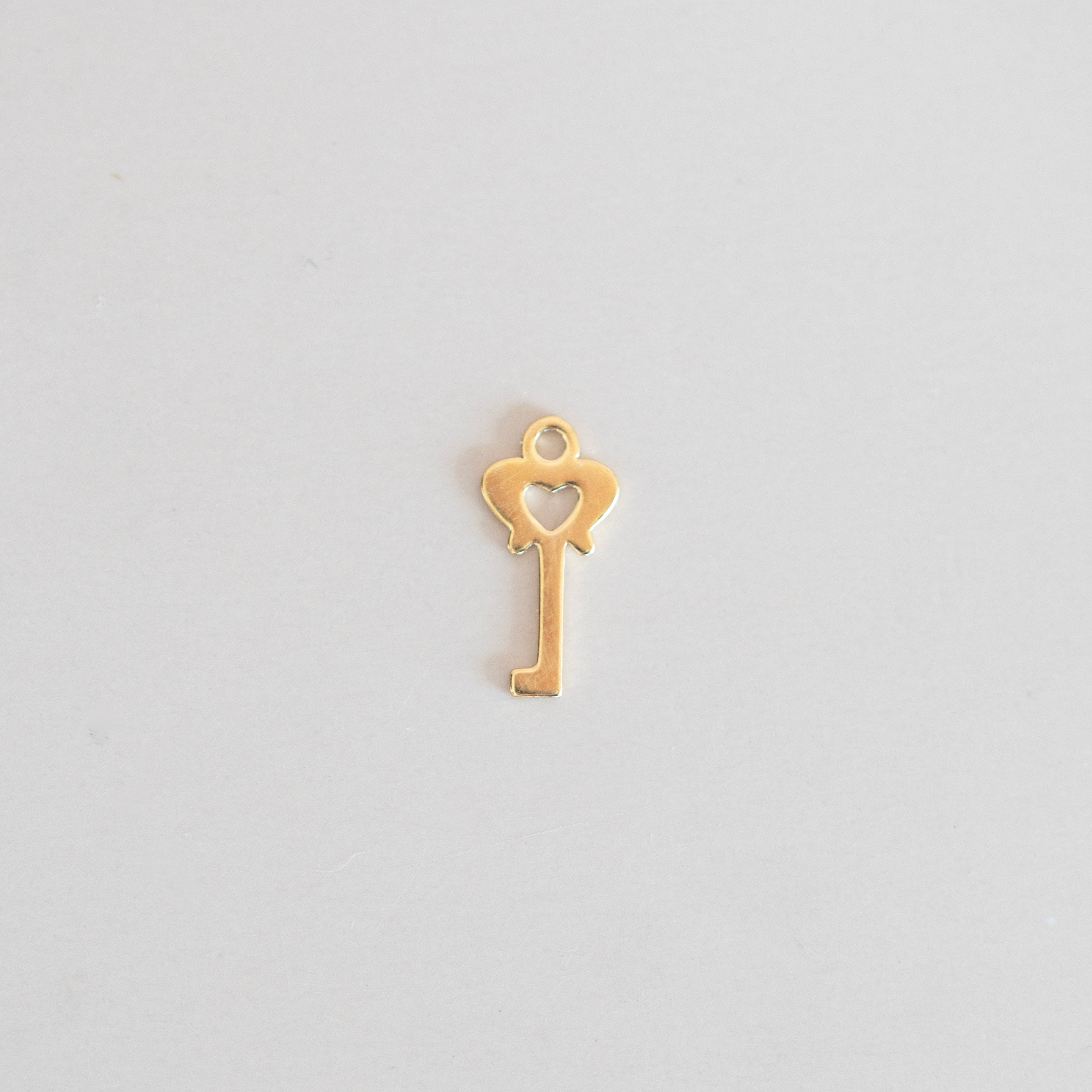Gold key-shaped pendant on a light gray background