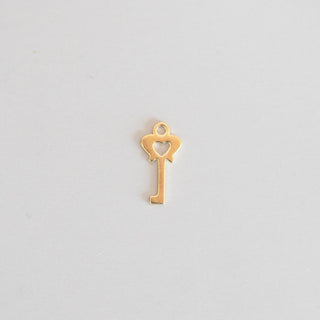 Gold key-shaped pendant on a light gray background