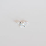 Small silver bow-shaped earring on a light gray background