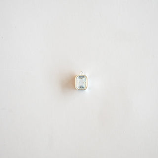 A small silver-toned pendant with a rectangular light blue gemstone, centered on a plain white background.