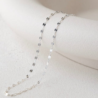 Silver chain necklace on white surface