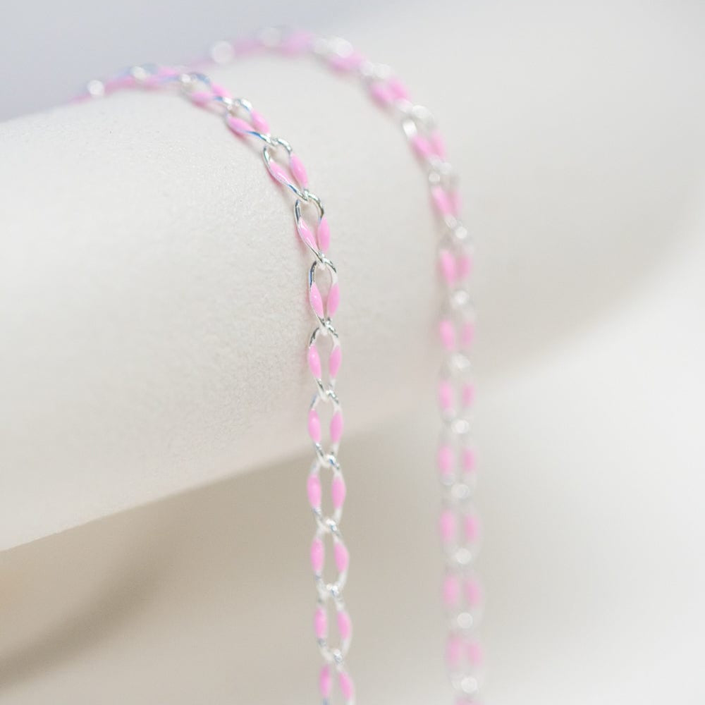 Pink and silver chain necklace on white background.