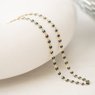 Gold chain necklace on a white surface.