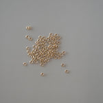 Small gold beads scattered on a gray background