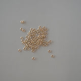 Small gold beads scattered on a gray background
