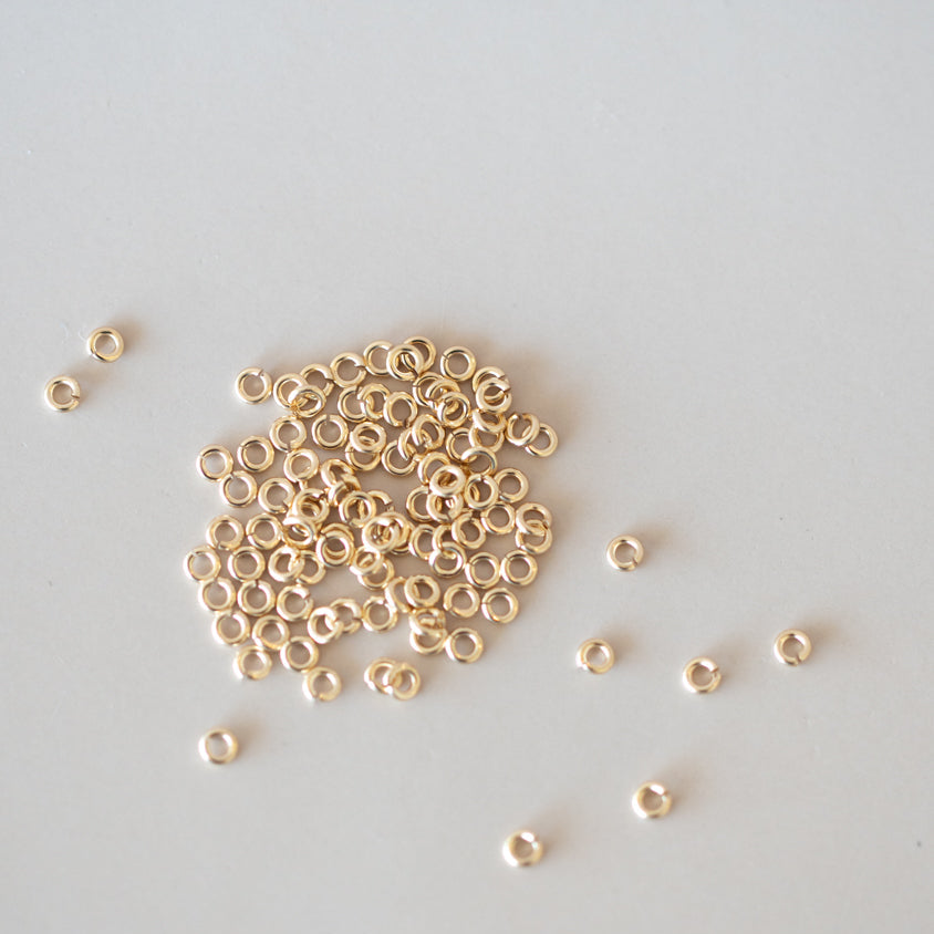 Small gold beads scattered on a light gray background