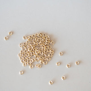 Small gold beads scattered on a light gray background