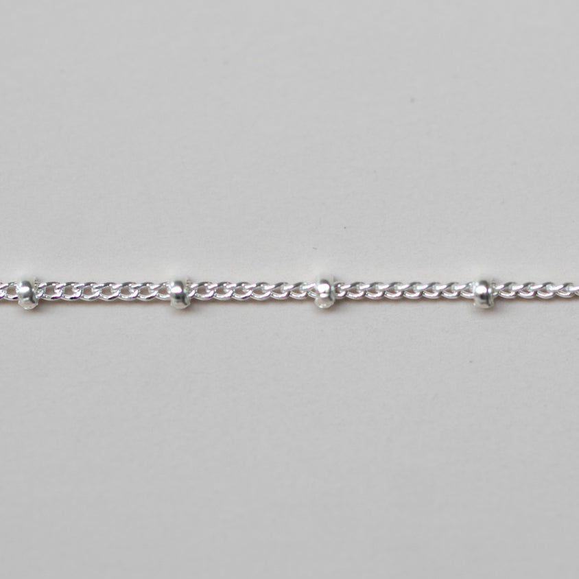 Silver chain bracelet on a light gray background