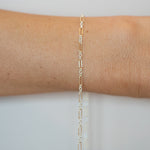 Gold bracelet on a person's wrist against a light gray background