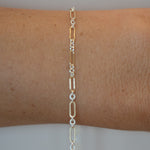 Silver chain bracelet on a wrist against a neutral background