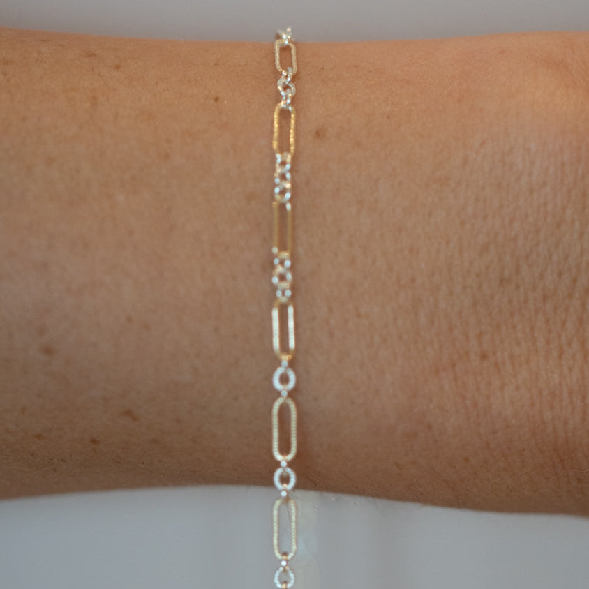 Silver chain bracelet on a wrist against a neutral background
