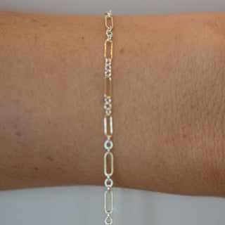 Silver chain bracelet on a wrist against a neutral background