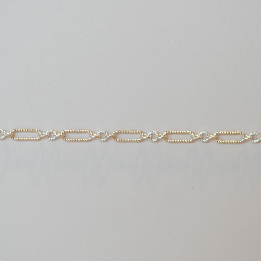 Gold chain bracelet on a light gray background