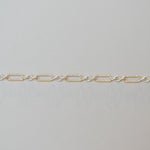 Gold chain bracelet on a light gray background
