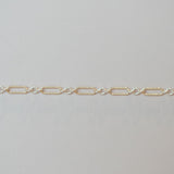 Gold chain bracelet on a light gray background