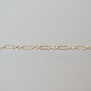 Gold chain bracelet on a light gray background