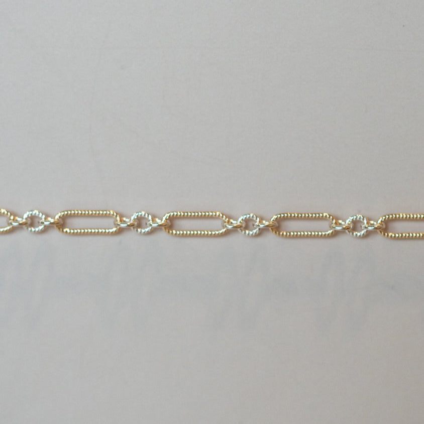 Gold chain bracelet on a light gray background