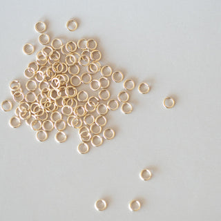 Gold jump rings scattered on a light gray background