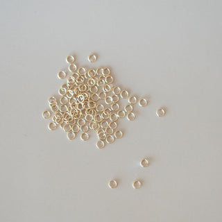 Small gold beads scattered on a light gray background