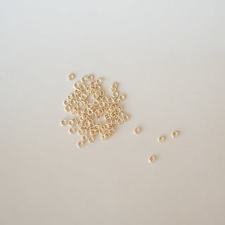 Small gold beads scattered on a light gray background