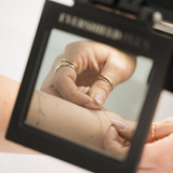 Hand with rings reflected in a mirror.