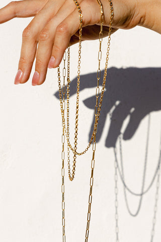Hand holding gold necklaces