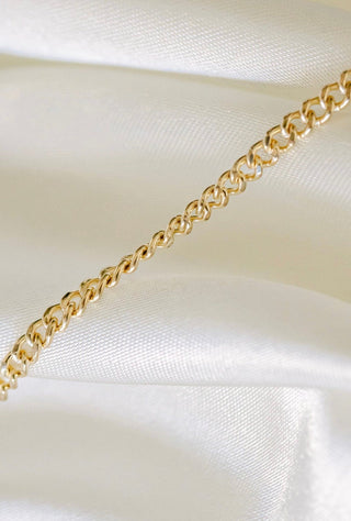 Gold chain necklace on white silk