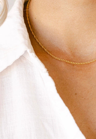 Gold necklace detail on white shirt