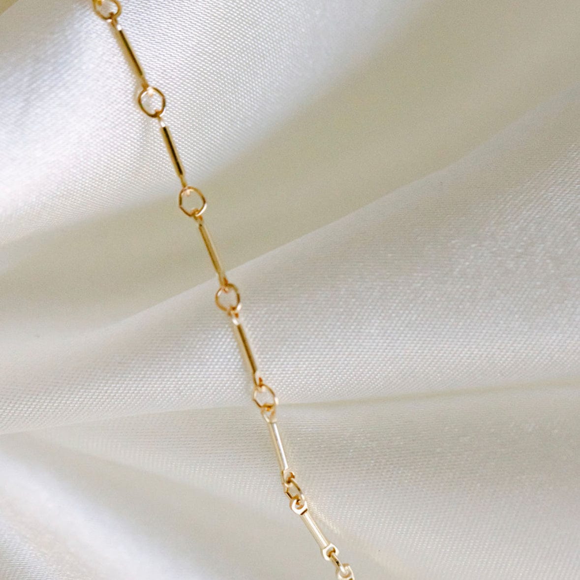 Gold chain necklace on white silk