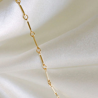 Gold chain necklace on white silk