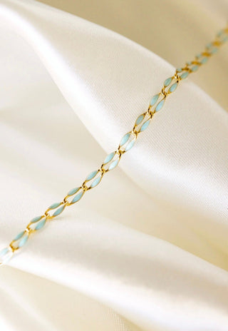 Gold and light blue chain necklace on satin
