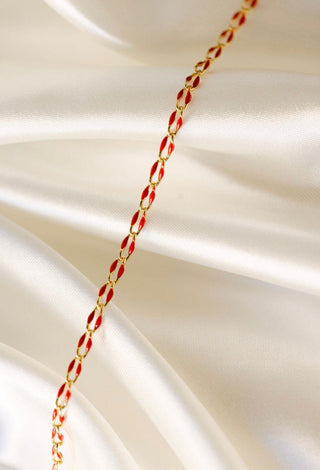 Gold and red chain bracelet on white satin