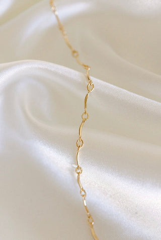 Gold chain necklace on white silk